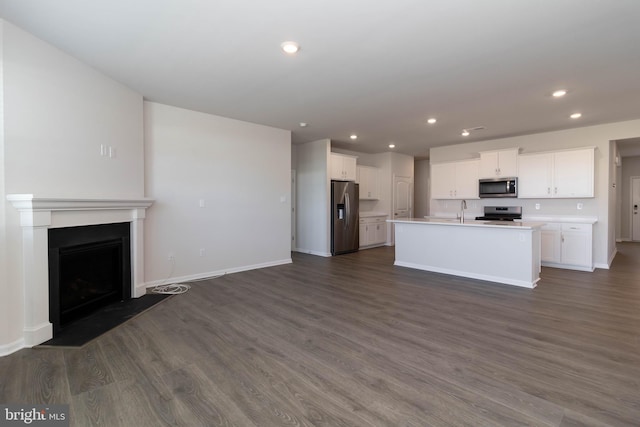 kitchen with dark hardwood / wood-style floors, sink, stainless steel appliances, an island with sink, and white cabinetry