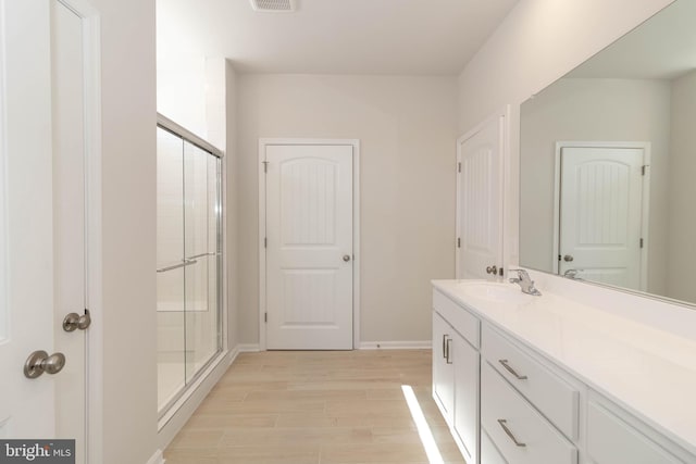 bathroom with walk in shower, vanity, and wood-type flooring