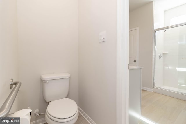 bathroom featuring hardwood / wood-style flooring, toilet, and a shower with door