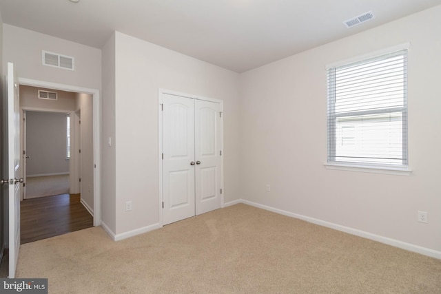 unfurnished bedroom featuring light carpet and a closet