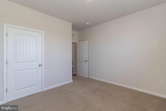 unfurnished bedroom with light colored carpet and a closet