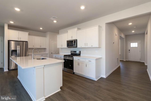 kitchen with stainless steel appliances, a kitchen island with sink, sink, and white cabinetry