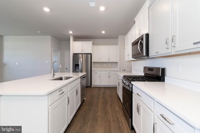 kitchen with an island with sink, dark hardwood / wood-style floors, stainless steel appliances, white cabinets, and sink