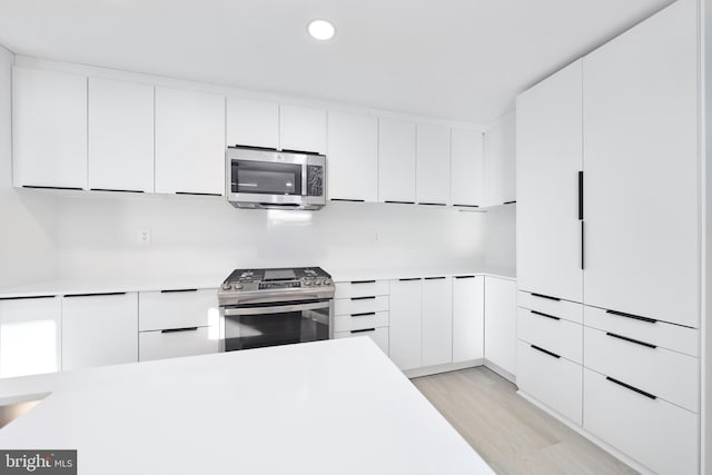 kitchen featuring light wood-type flooring, stainless steel appliances, and white cabinets