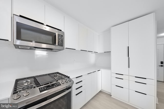 kitchen with light hardwood / wood-style flooring, stainless steel appliances, and white cabinetry