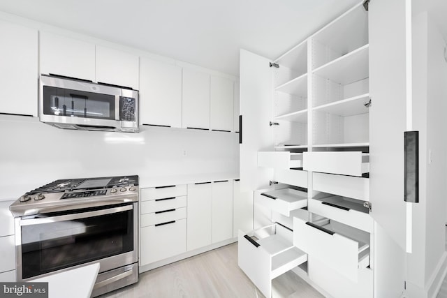 kitchen with appliances with stainless steel finishes, light hardwood / wood-style flooring, and white cabinets