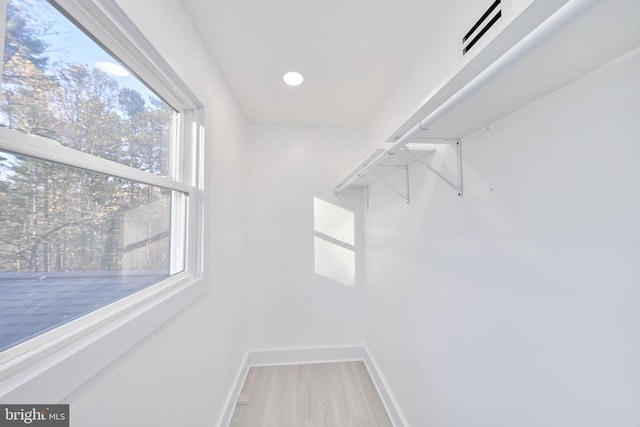 walk in closet with light hardwood / wood-style floors