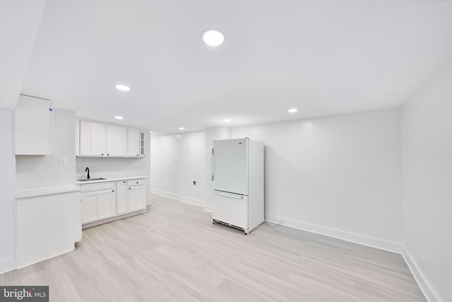 interior space featuring white cabinets, light wood-type flooring, sink, and white refrigerator