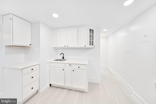 kitchen featuring white cabinets, sink, and light hardwood / wood-style floors