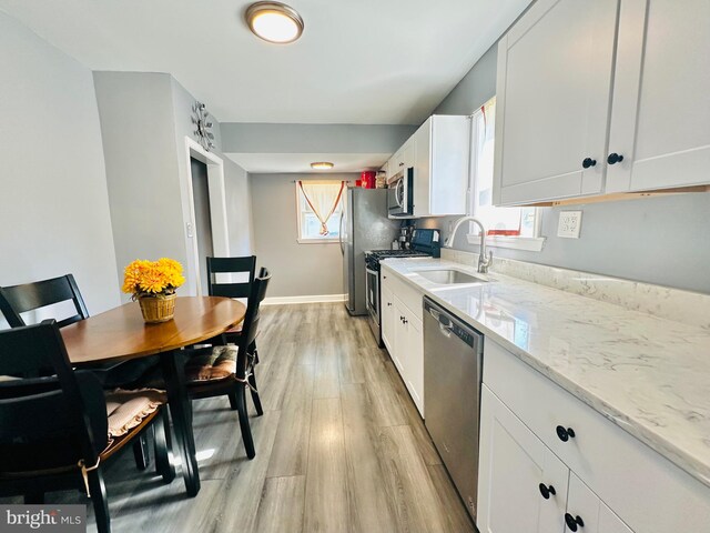 kitchen featuring plenty of natural light, white cabinets, light hardwood / wood-style floors, and appliances with stainless steel finishes