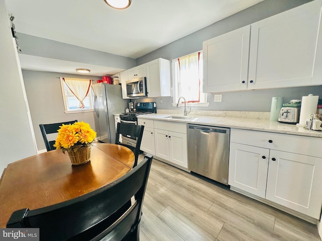 kitchen with white cabinets, stainless steel appliances, a wealth of natural light, and sink