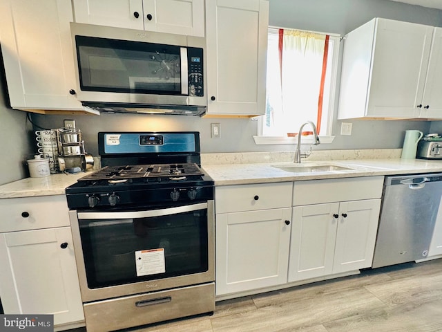 kitchen featuring light wood-type flooring, white cabinetry, sink, and appliances with stainless steel finishes