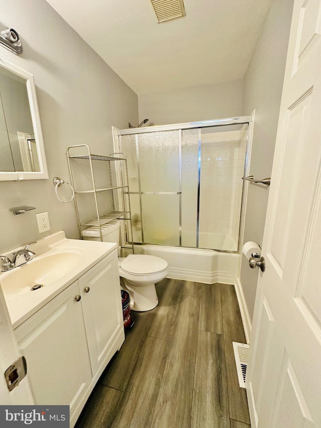 full bathroom with enclosed tub / shower combo, vanity, wood-type flooring, and toilet