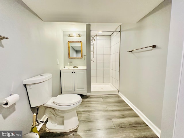 bathroom featuring tiled shower, hardwood / wood-style floors, vanity, and toilet