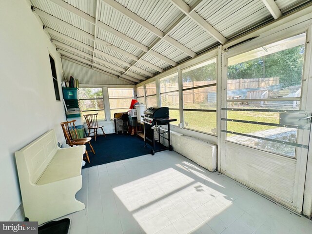 sunroom / solarium featuring vaulted ceiling with beams and a wealth of natural light