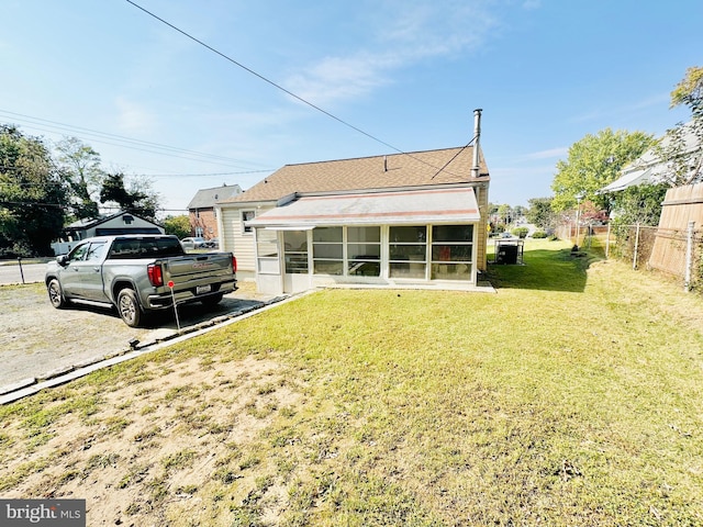 back of house with a lawn and a sunroom