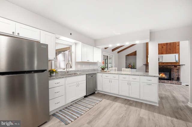 kitchen featuring appliances with stainless steel finishes, light wood-type flooring, beamed ceiling, and white cabinetry