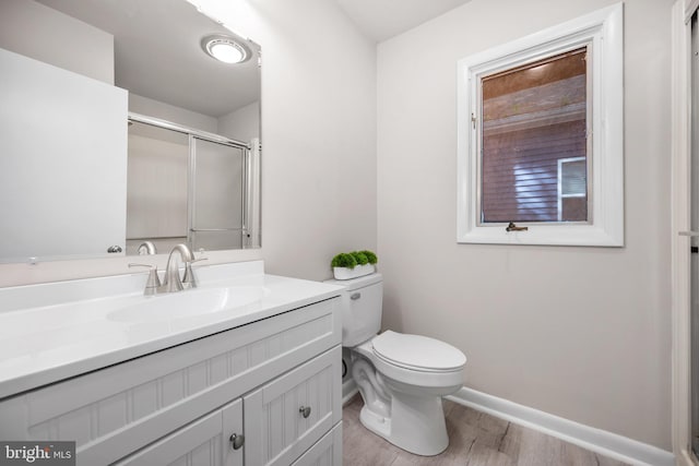 bathroom featuring wood-type flooring, vanity, toilet, and an enclosed shower