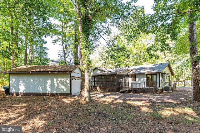 back of house with cooling unit, a garage, a wooden deck, and a sunroom