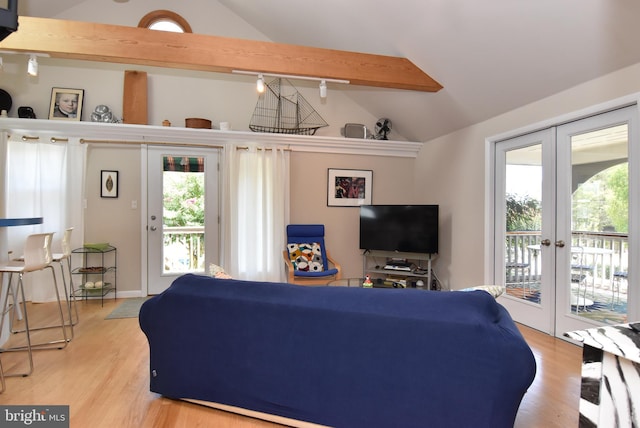 living room featuring lofted ceiling with beams, a wealth of natural light, french doors, and light hardwood / wood-style flooring