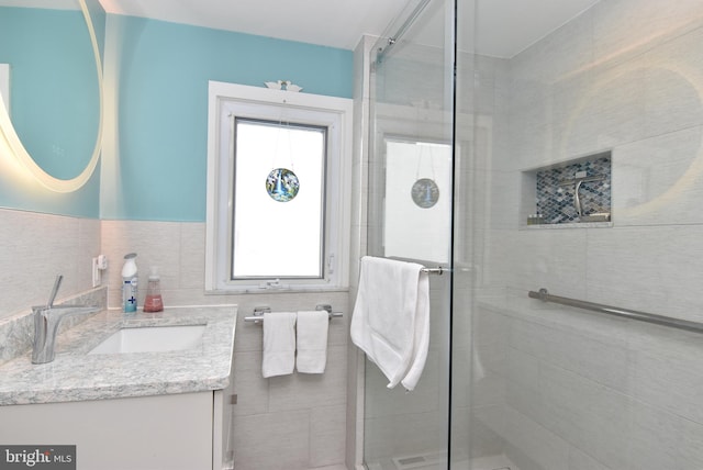 bathroom with vanity, tile walls, plenty of natural light, and a shower with door