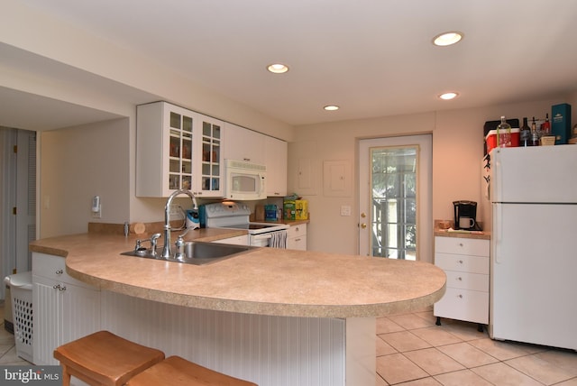 kitchen featuring sink, white appliances, white cabinetry, and a breakfast bar