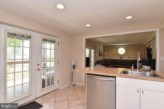 kitchen featuring light tile patterned floors, sink, stainless steel dishwasher, french doors, and white cabinetry