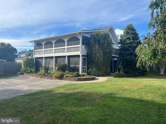 view of front of house with a front yard and a sunroom