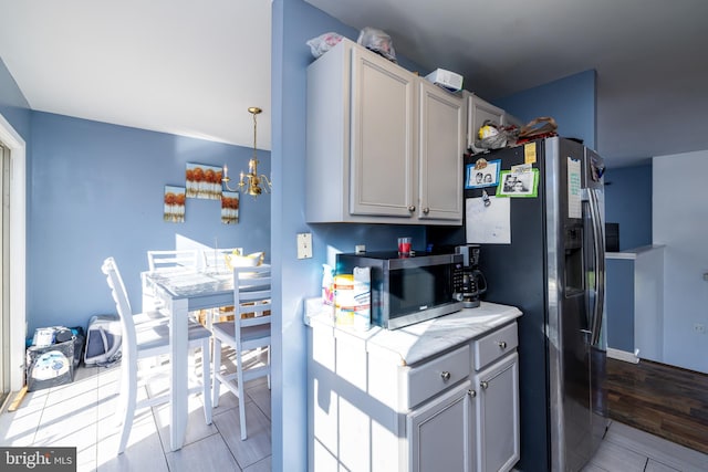 kitchen featuring stainless steel appliances, gray cabinetry, pendant lighting, a notable chandelier, and light hardwood / wood-style flooring