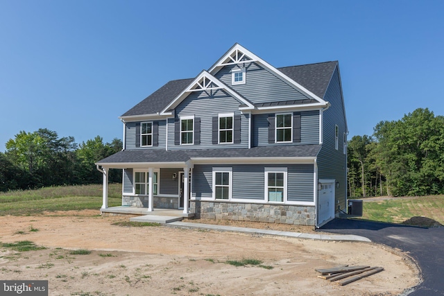 view of front of property featuring central AC unit, a garage, and covered porch