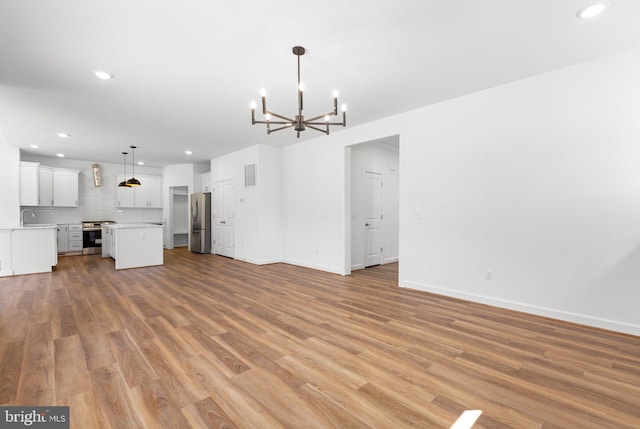 unfurnished living room featuring a notable chandelier, sink, and light hardwood / wood-style floors