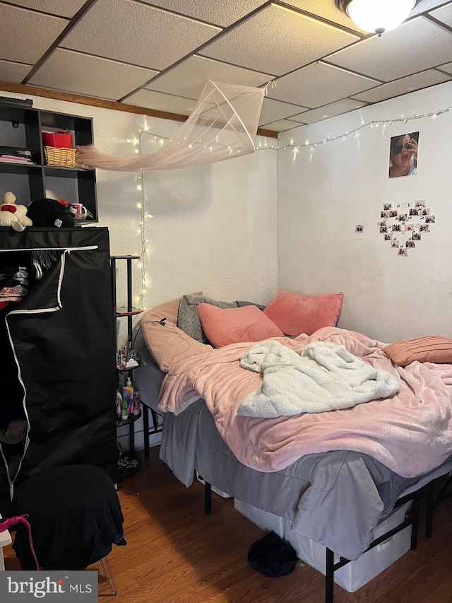 bedroom with a paneled ceiling and hardwood / wood-style floors