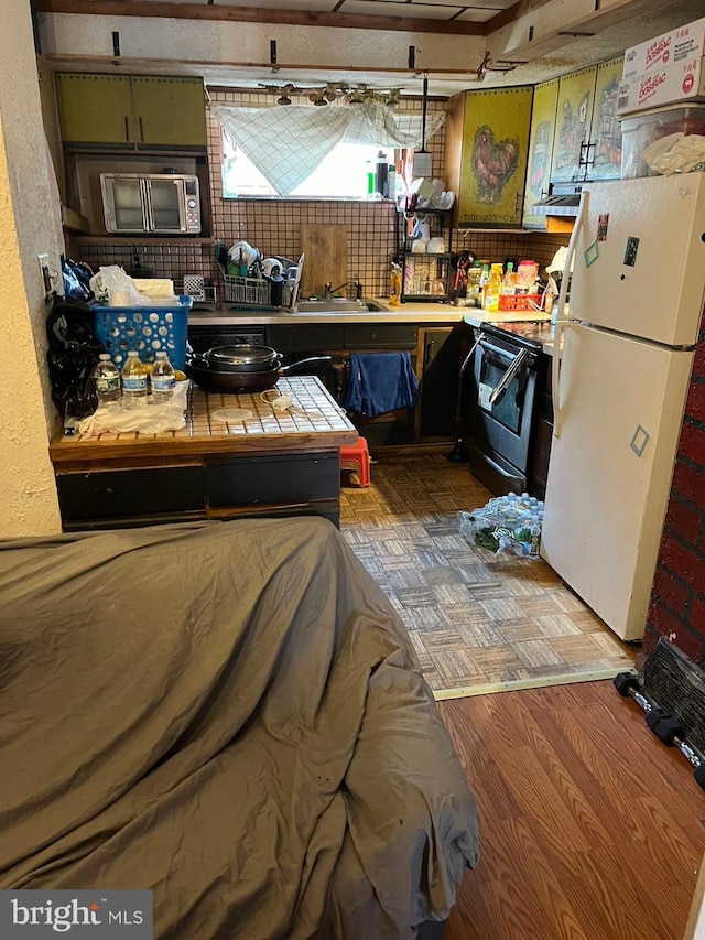 kitchen featuring electric range, hardwood / wood-style flooring, tile counters, sink, and white refrigerator