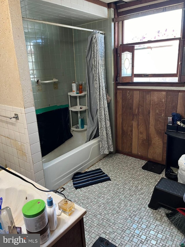 bathroom with tile walls, shower / tub combo with curtain, and tile patterned floors