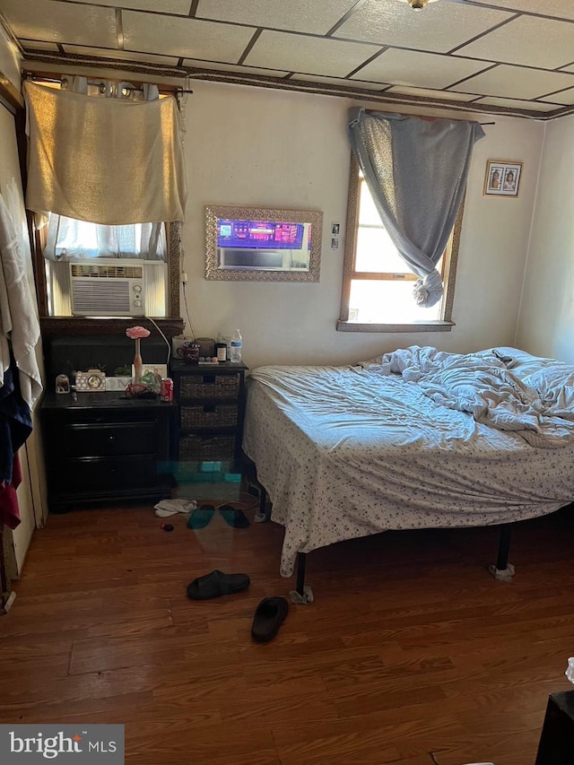 bedroom with cooling unit, a paneled ceiling, and hardwood / wood-style flooring