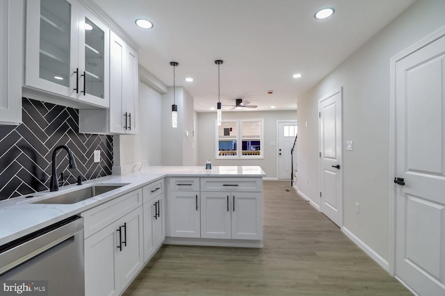 kitchen featuring white cabinetry, backsplash, ceiling fan, dishwasher, and a sink