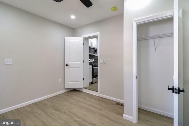 unfurnished bedroom with a closet, baseboards, recessed lighting, and wood finished floors