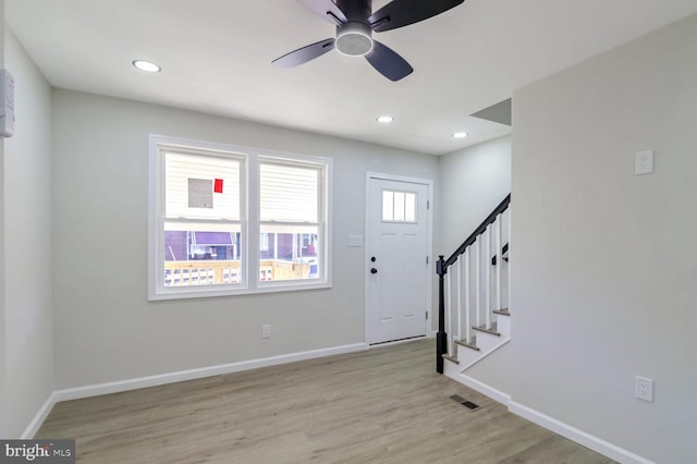 entryway featuring baseboards, stairs, visible vents, ceiling fan, and wood finished floors