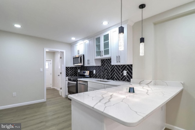 kitchen with tasteful backsplash, baseboards, white cabinets, light wood-type flooring, and stainless steel appliances