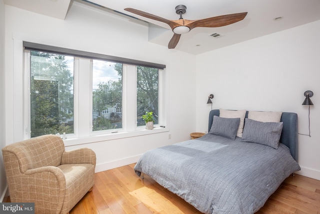 bedroom with ceiling fan, light hardwood / wood-style flooring, and multiple windows