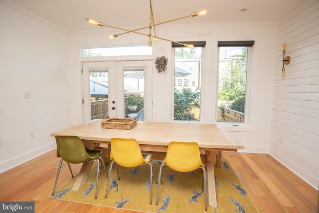 dining area featuring french doors, crown molding, light hardwood / wood-style floors, and a chandelier