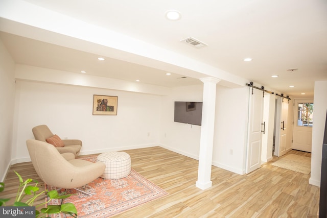 living area with light wood-type flooring and a barn door