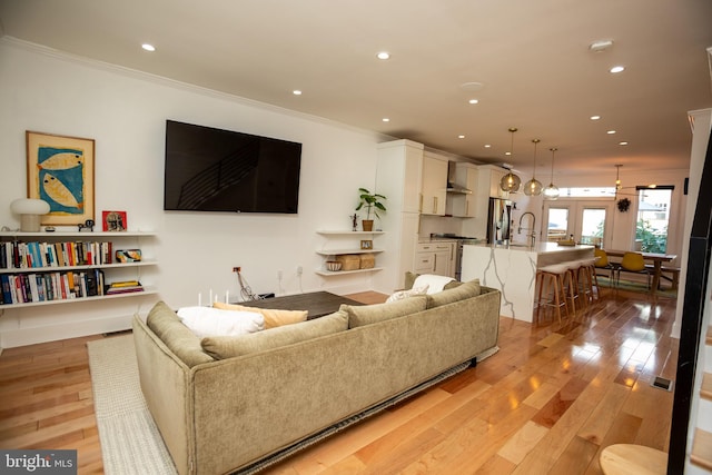 living room with ornamental molding and light hardwood / wood-style flooring