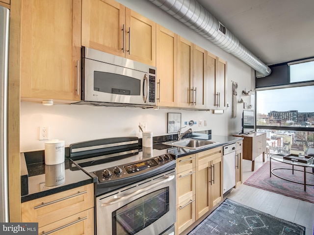 kitchen featuring appliances with stainless steel finishes, light wood-type flooring, sink, and light brown cabinets