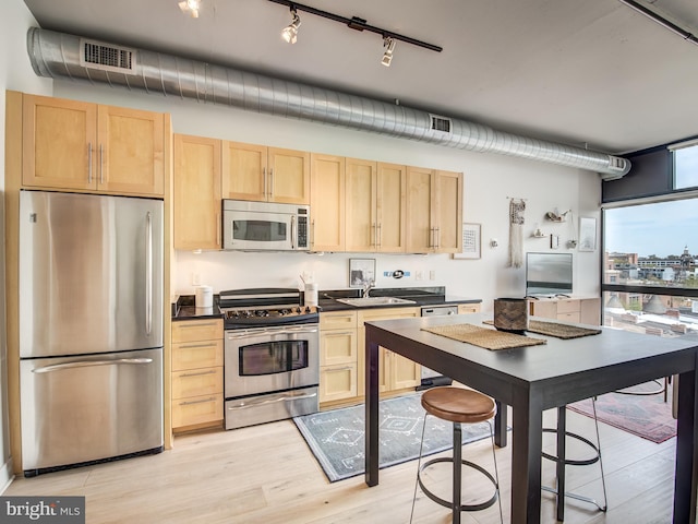 kitchen featuring appliances with stainless steel finishes, light wood-type flooring, sink, and light brown cabinets