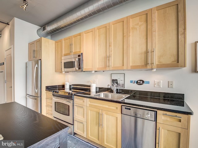 kitchen featuring stainless steel appliances, light brown cabinetry, and sink