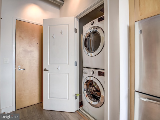 washroom with stacked washer / dryer and dark hardwood / wood-style flooring