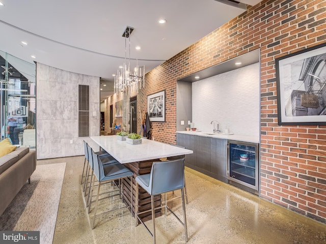 interior space with beverage cooler, brick wall, dark brown cabinetry, and a kitchen bar