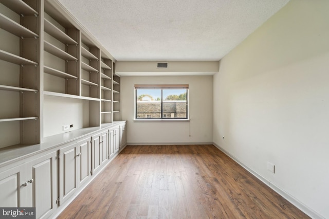 spare room featuring a textured ceiling and dark hardwood / wood-style flooring