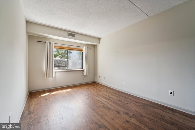 unfurnished room with a textured ceiling and dark wood-type flooring